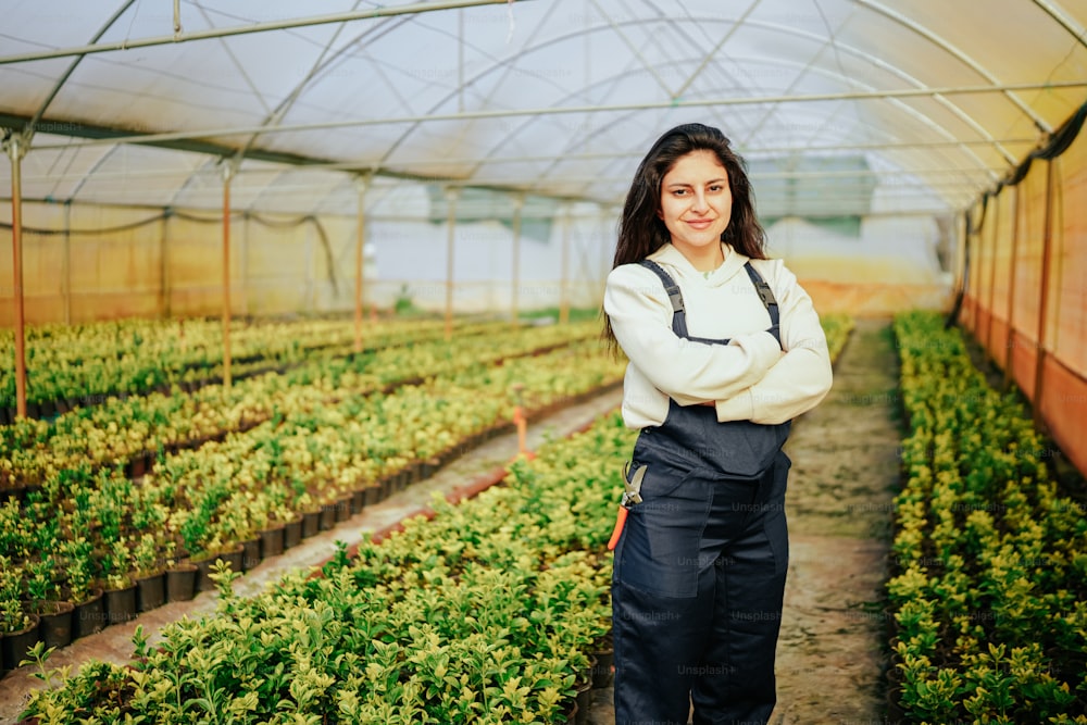 a woman standing in a greenhouse with her arms crossed