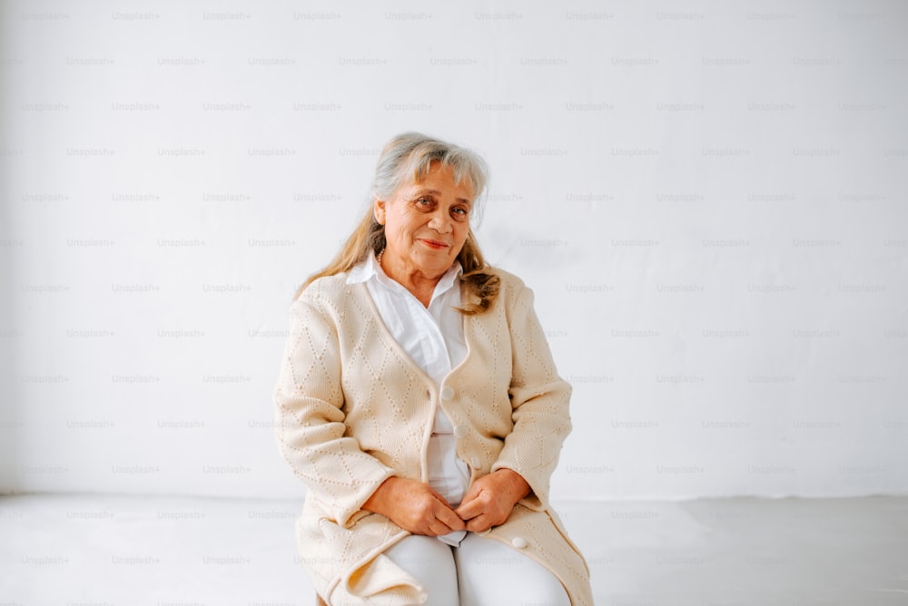 uma mulher mais velha sentada em uma superfície branca