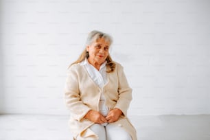 an older woman sitting on a white surface
