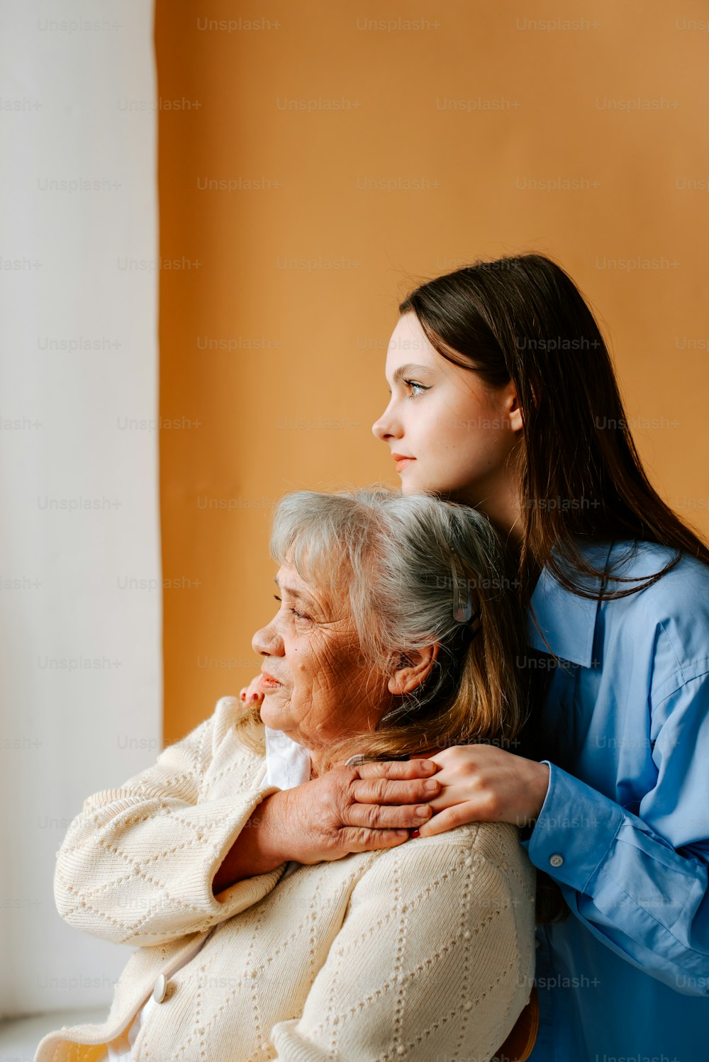 a woman hugging an older woman in a chair