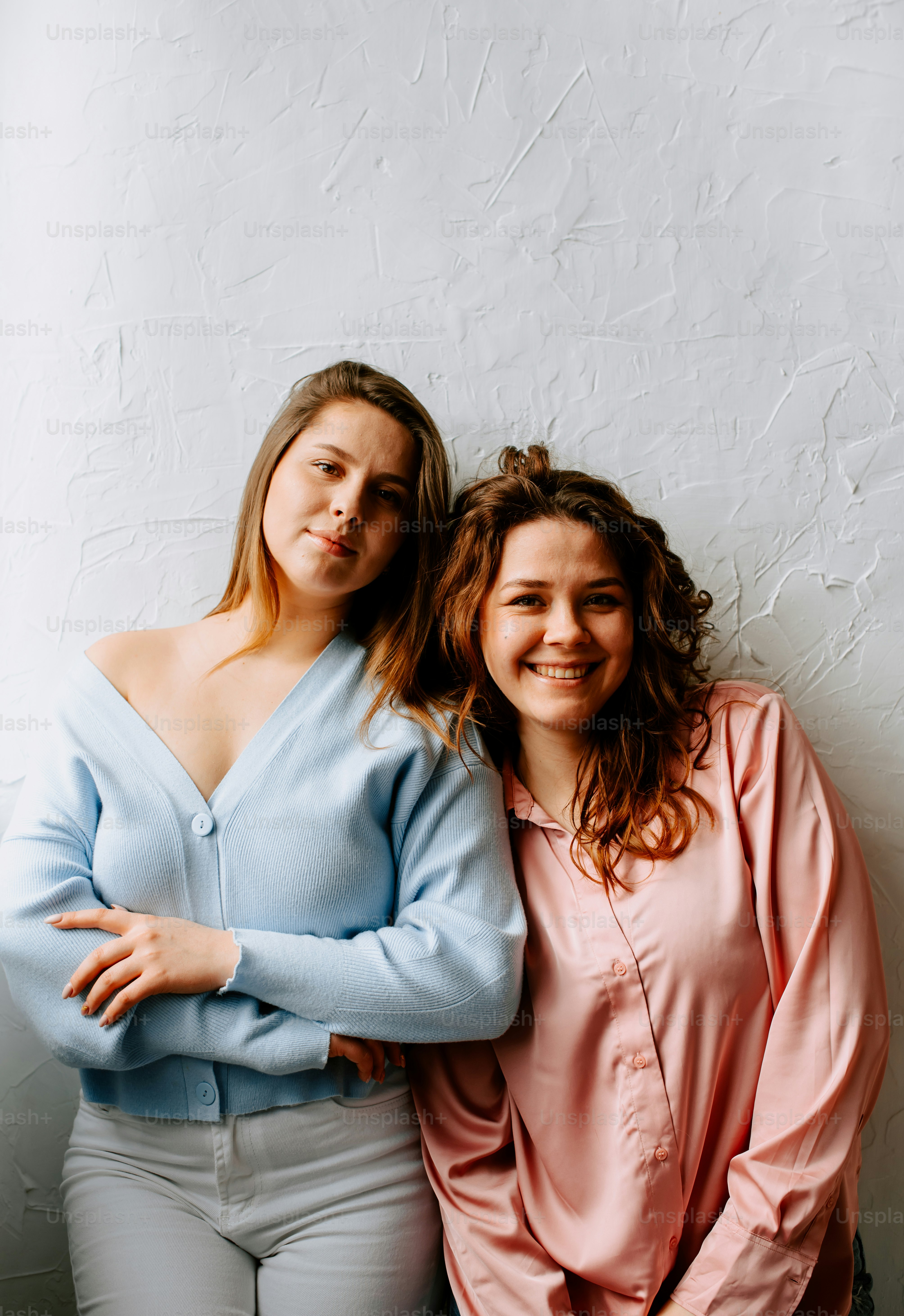 Deux femmes debout l’une à côté de l’autre devant un mur blanc