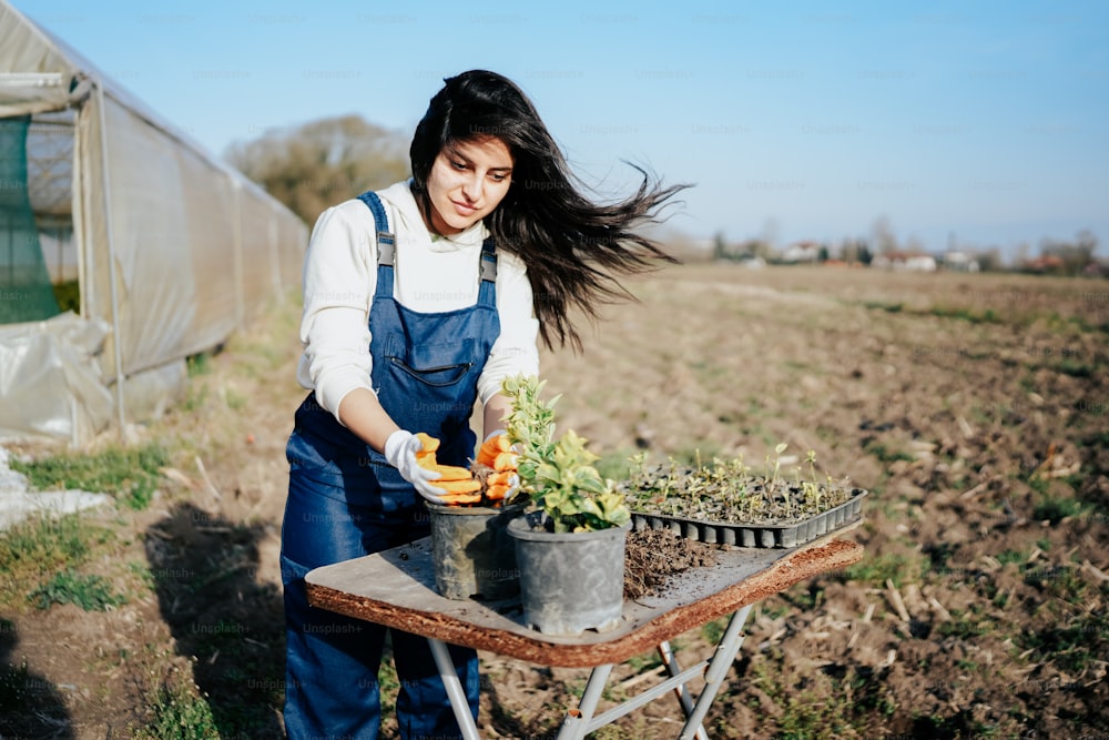 a woman in overalls holding a bucket full of vegetables