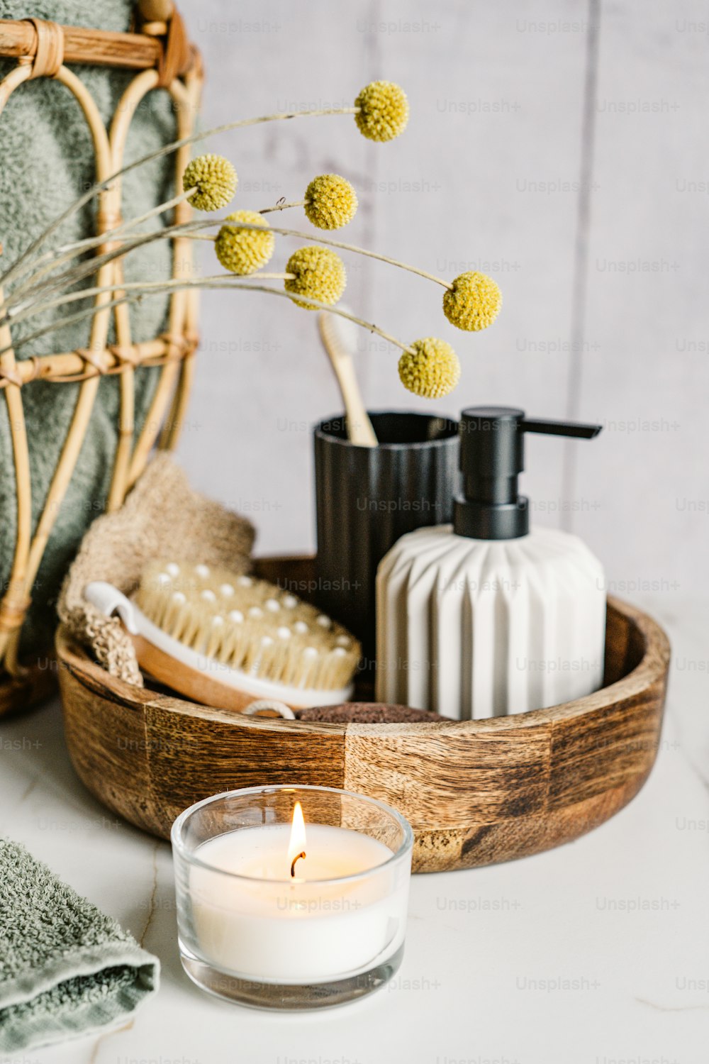 a basket with a candle, soap, brush and soap dispenser