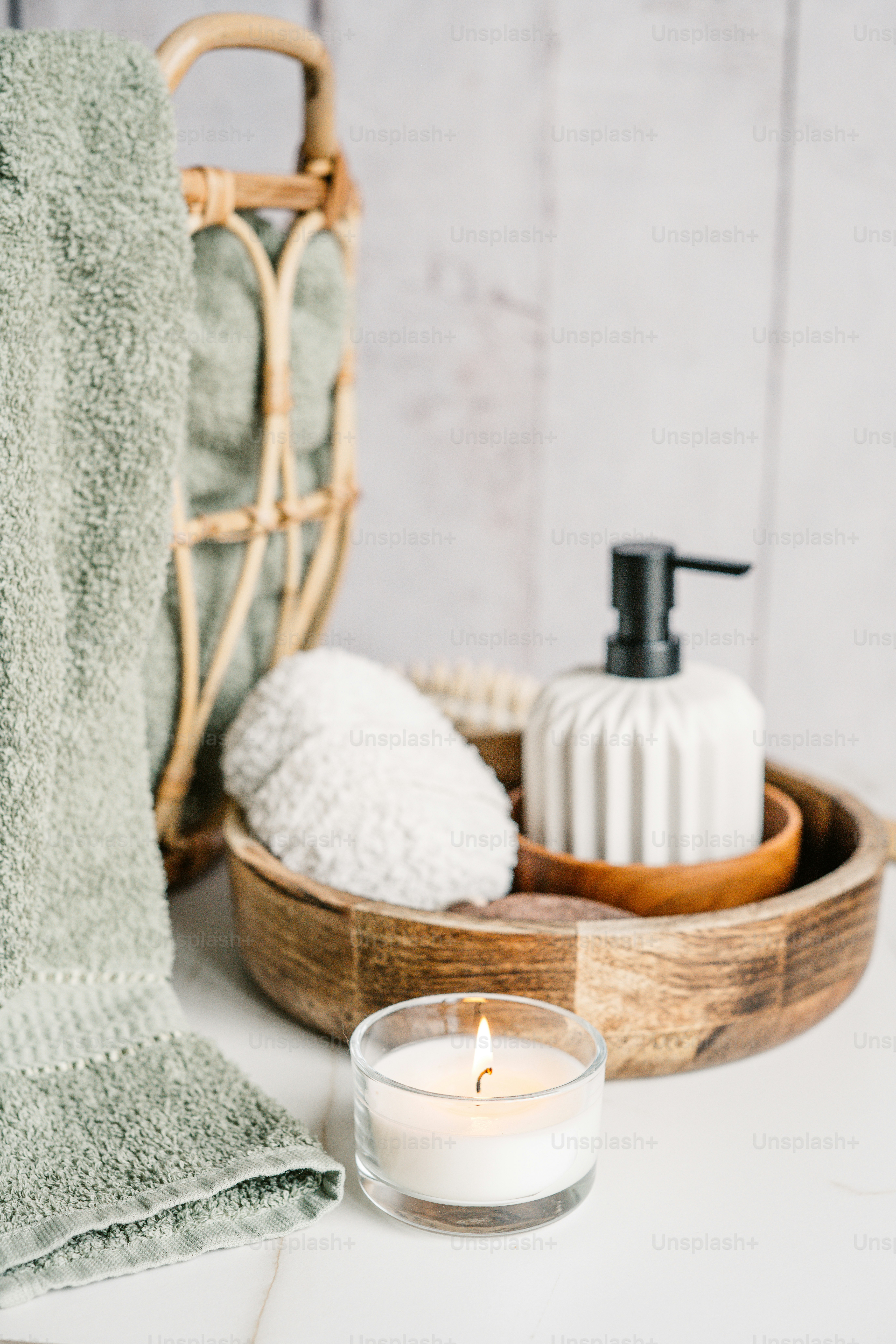 Una vela blanca sentada encima de una mesa junto a una canasta