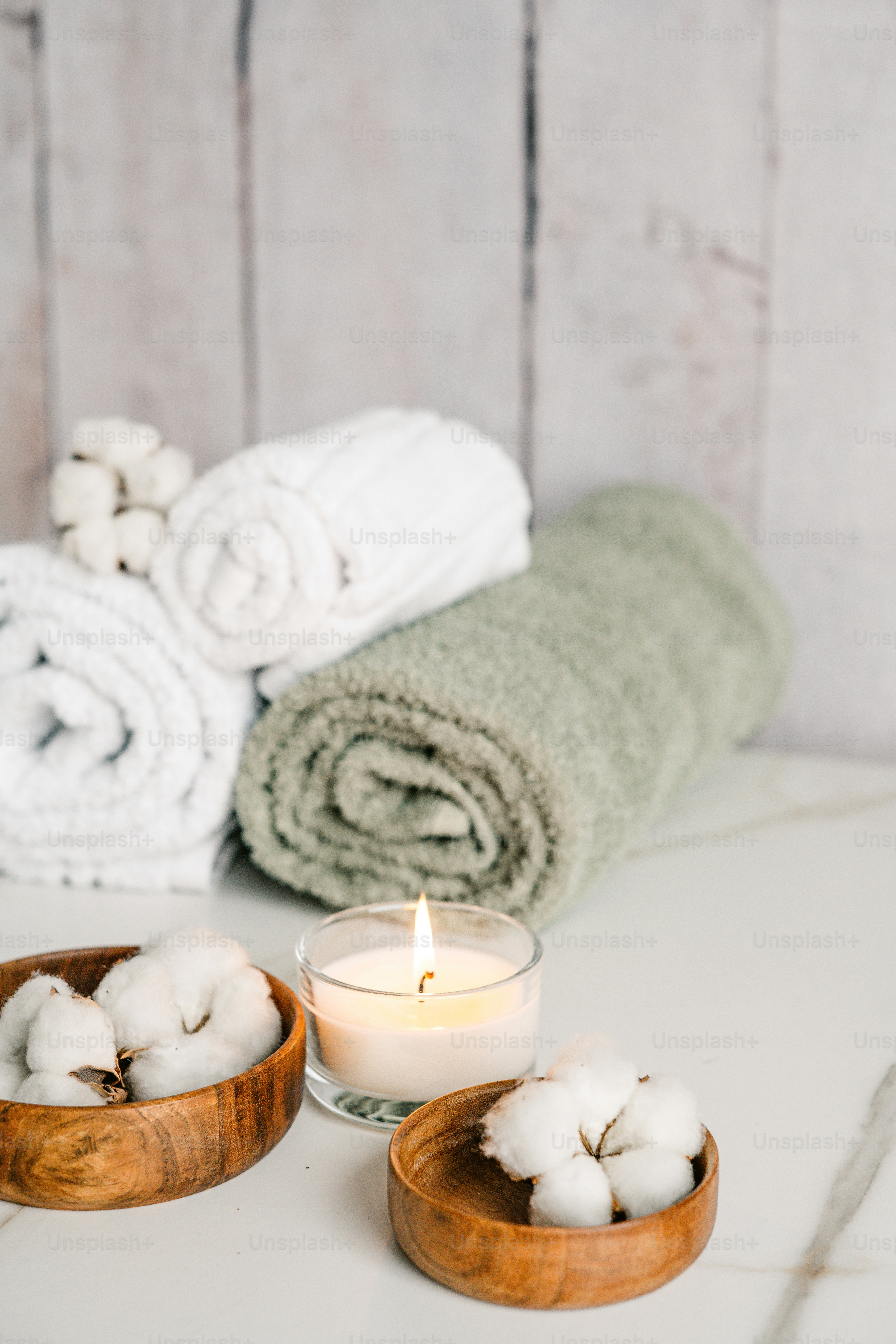 Un cuenco de madera lleno de algodón junto a una vela