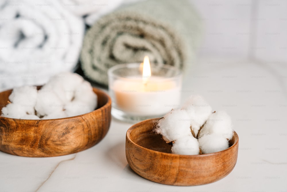two wooden bowls filled with cotton next to a candle