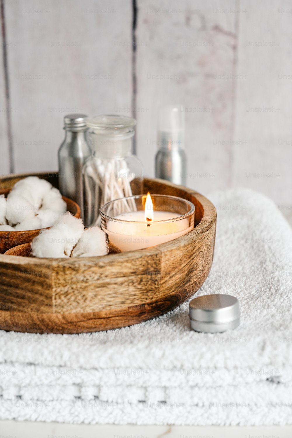 a wooden bowl filled with cotton and a candle
