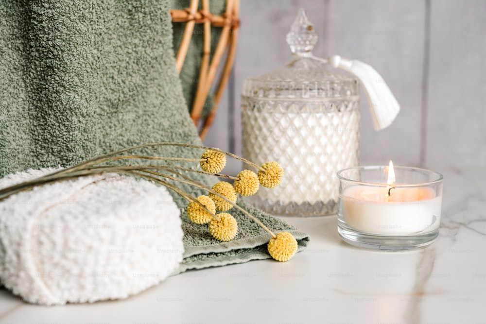 a towel, a candle, and some flowers on a table
