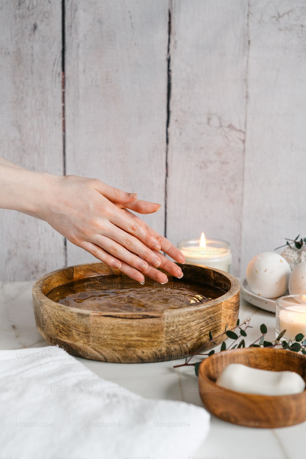a person reaching for a candle in a wooden bowl