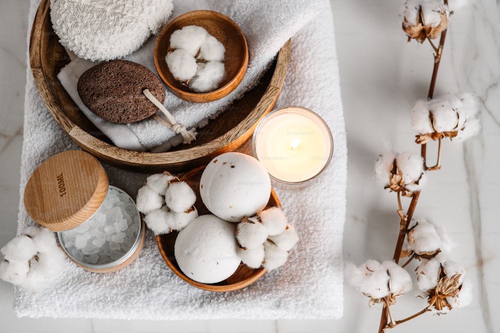 a bowl of cotton and a candle on a towel