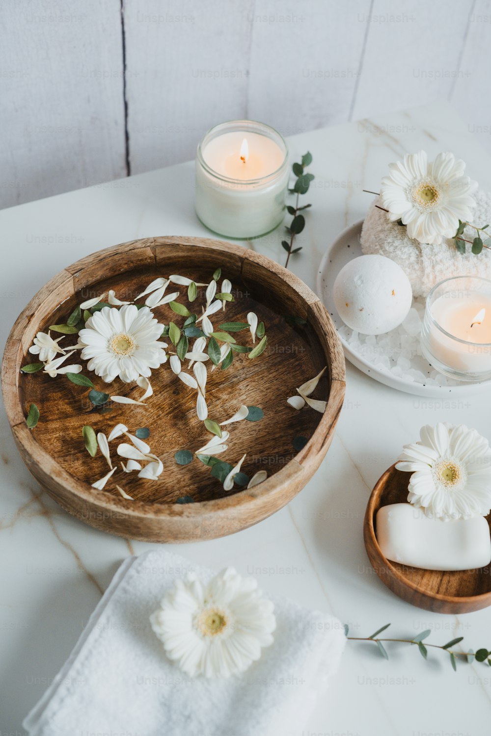 a wooden bowl filled with flowers next to candles