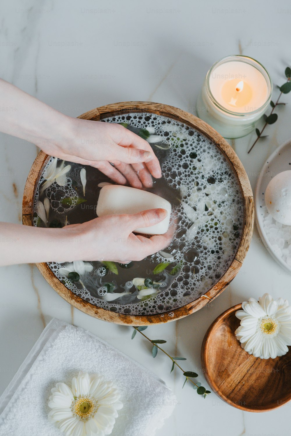 a woman is washing her hands in a bowl of soap