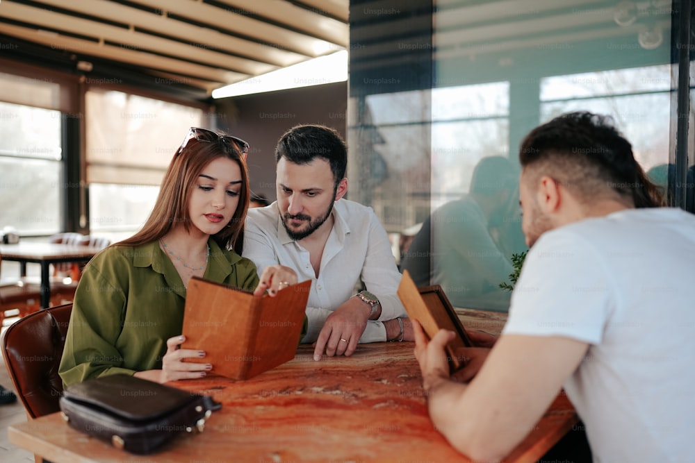 a man and a woman sitting at a table looking at a book