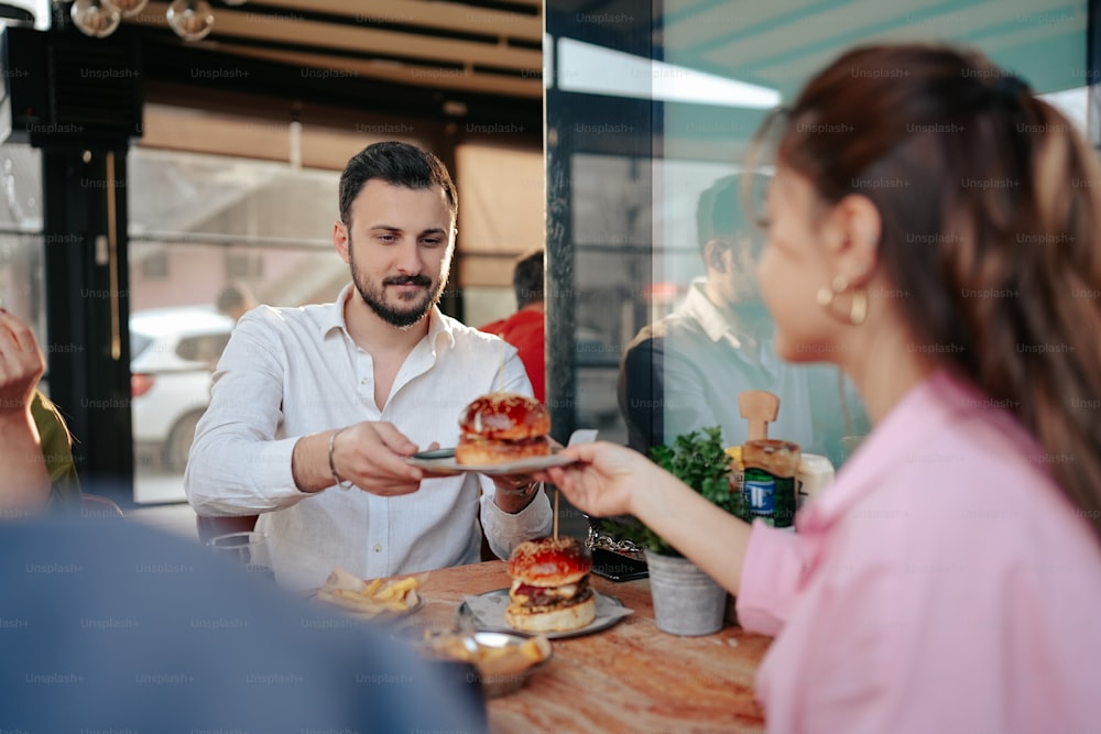 a man handing a plate of food to a woman