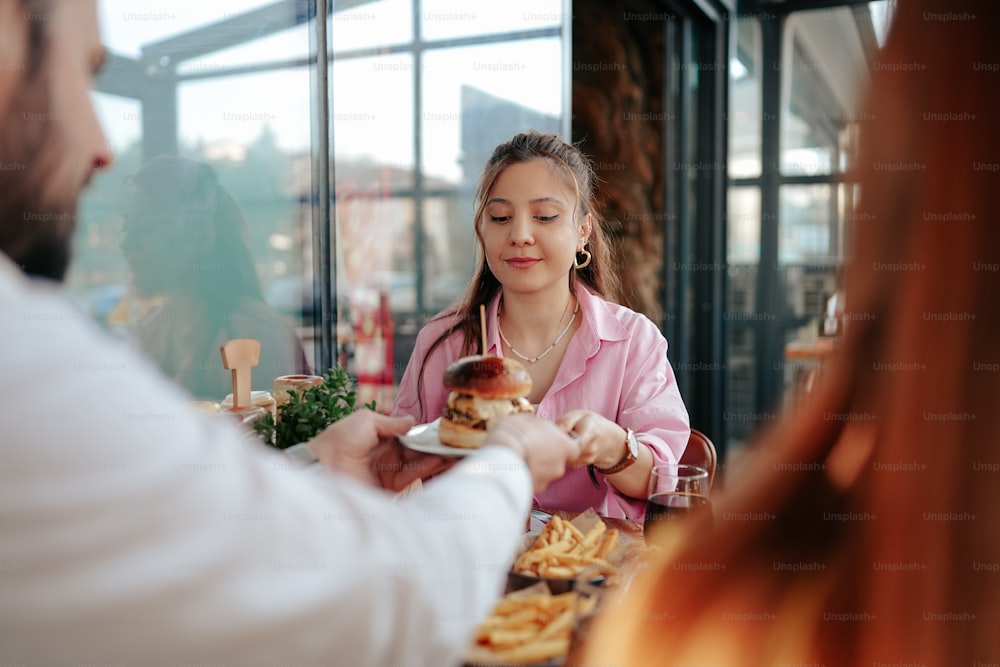 a woman is serving a hamburger to a man