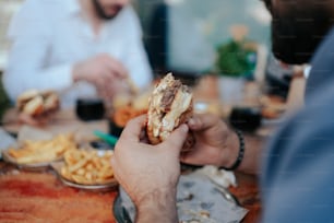 Un hombre comiendo un sándwich en una mesa con otras personas