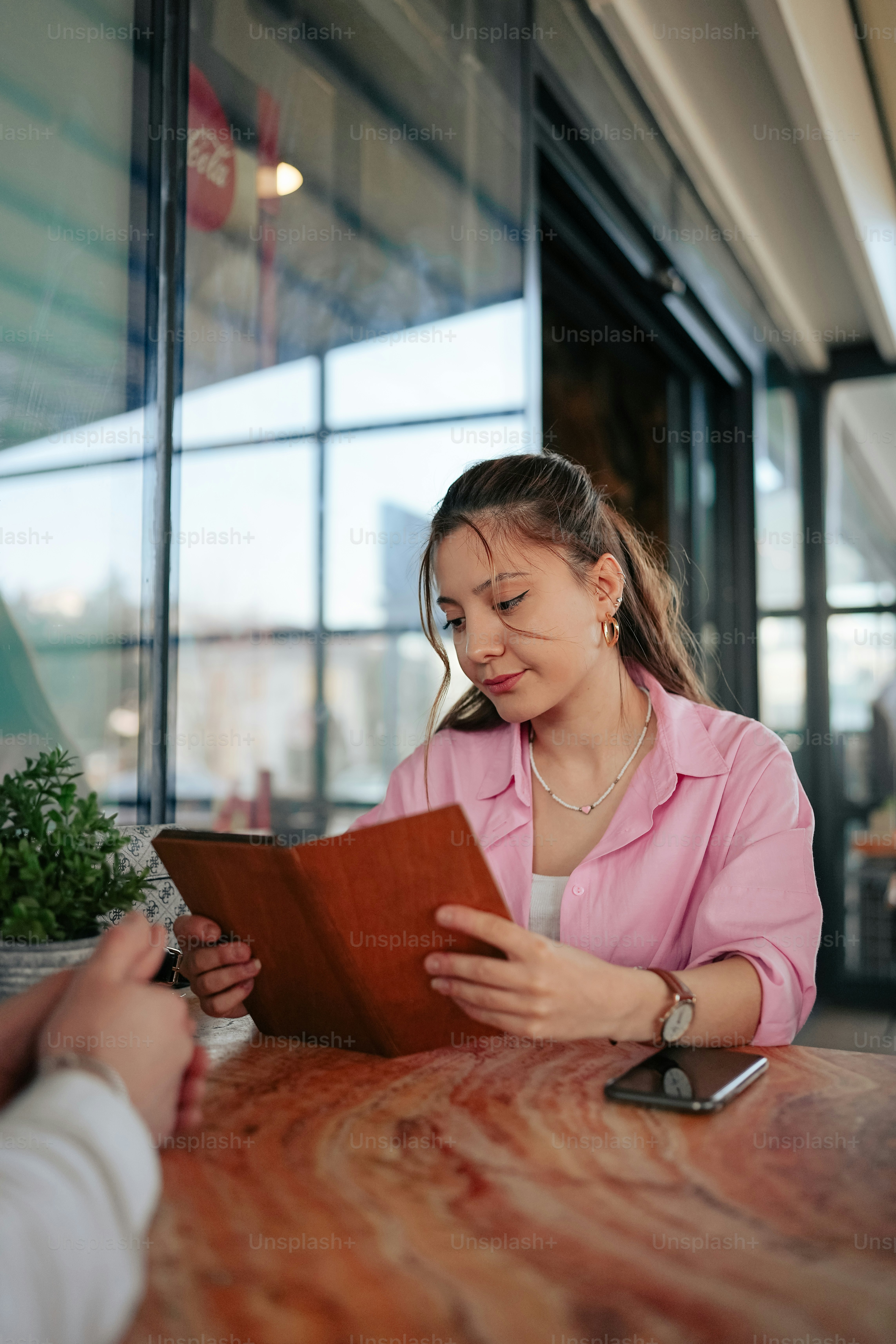 a woman sitting at a table reading a book