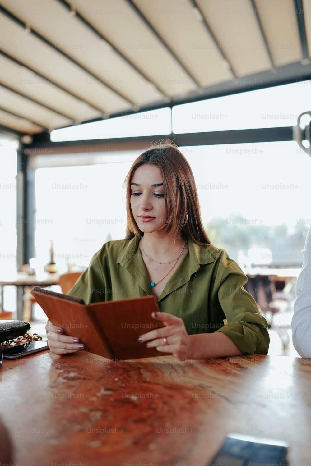 a woman sitting at a table looking at a tablet