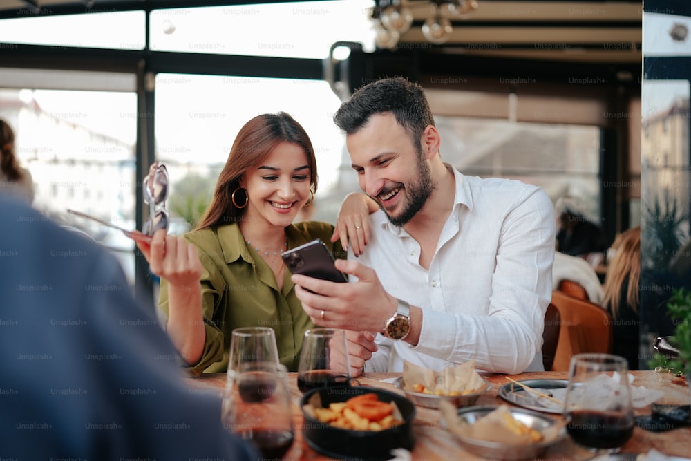 Un homme et une femme assis à une table regardant un téléphone portable