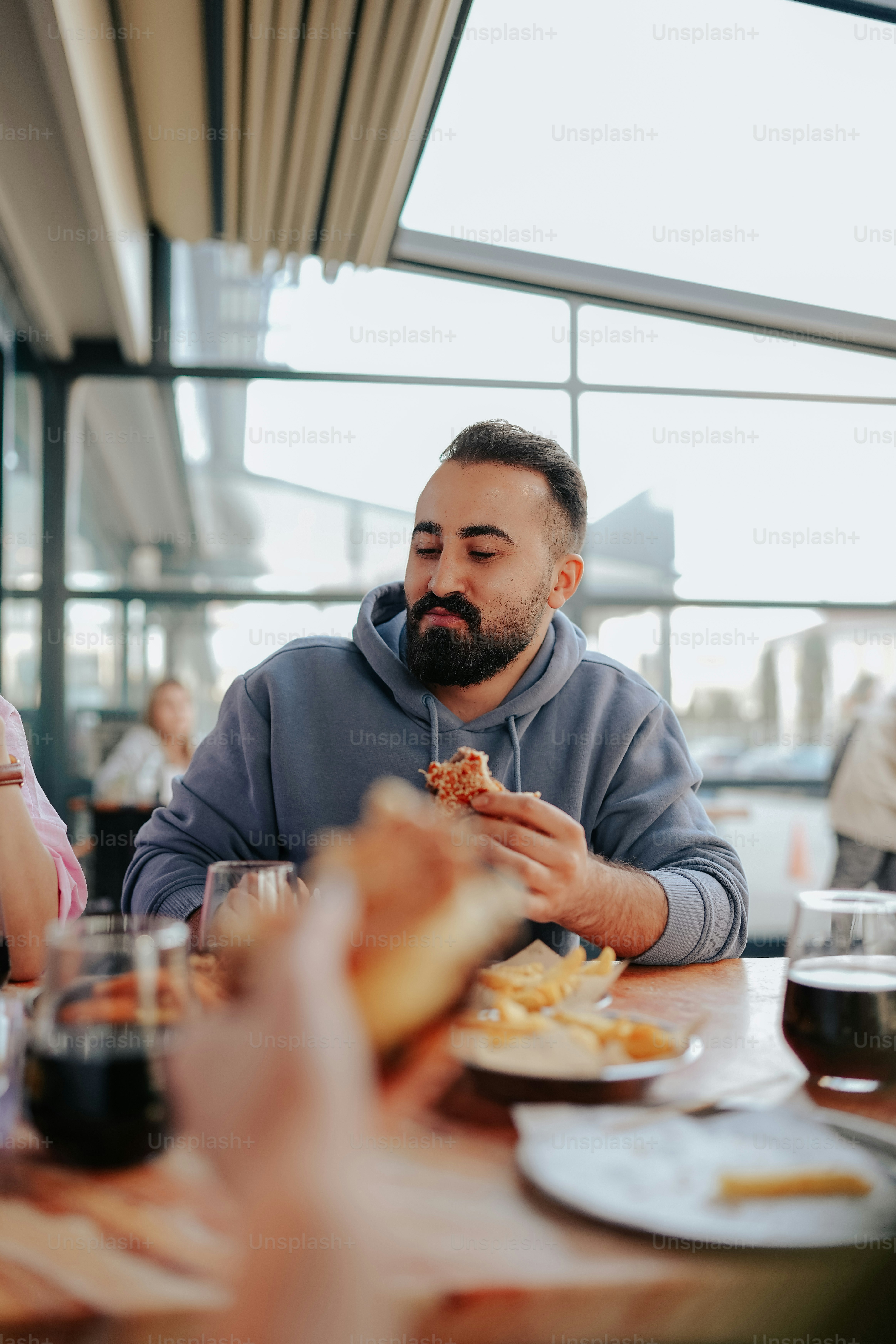 a man sitting at a table eating a piece of pizza