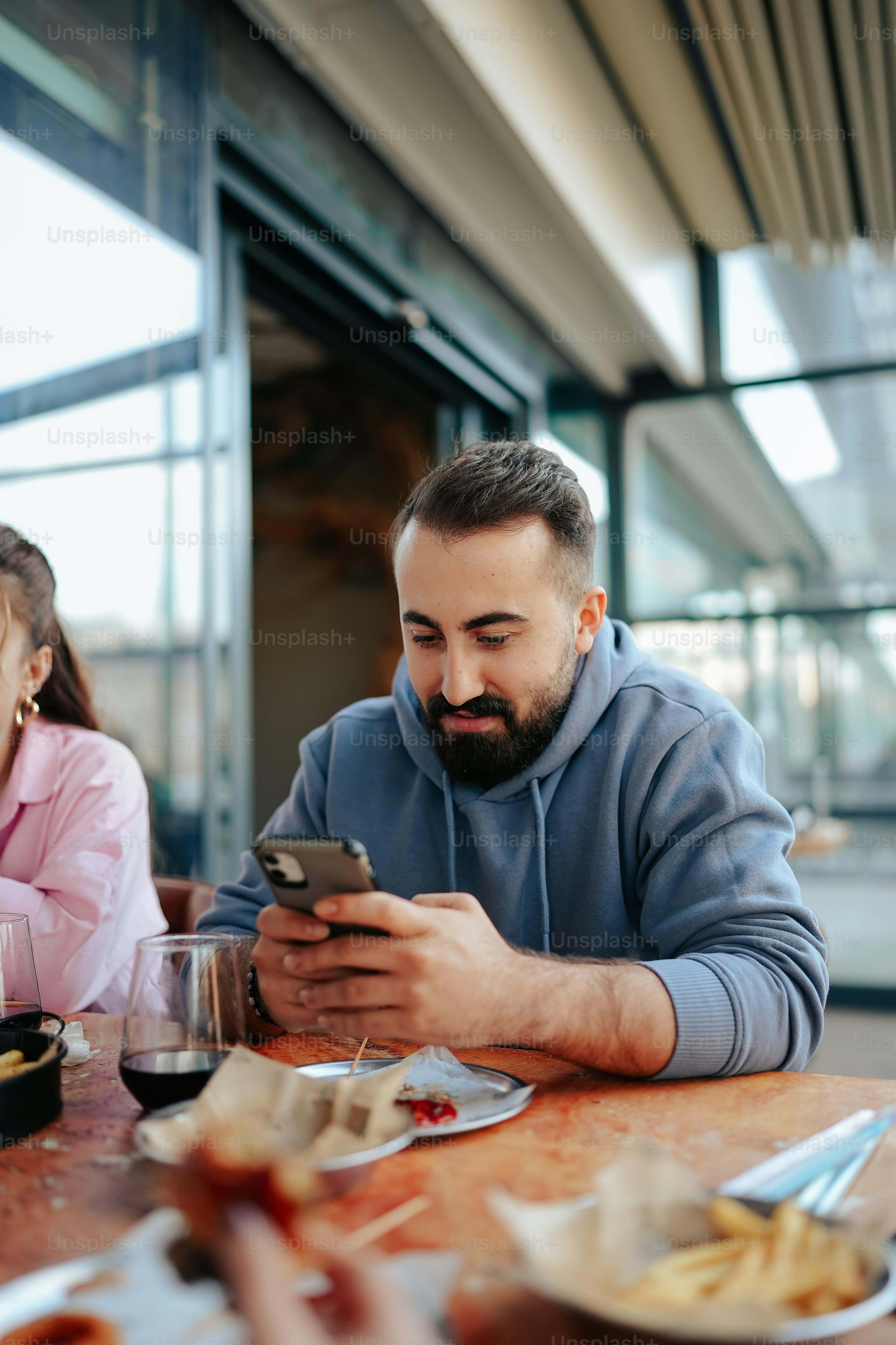 a man sitting at a table looking at a cell phone