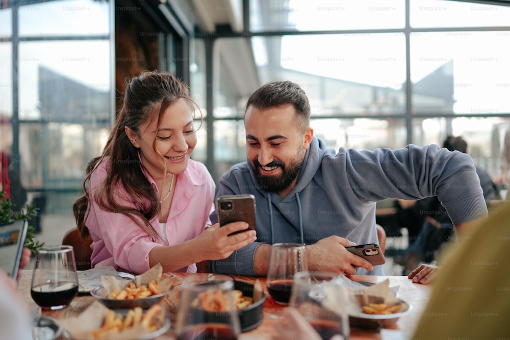 a man and woman sitting at a table looking at a cell phone