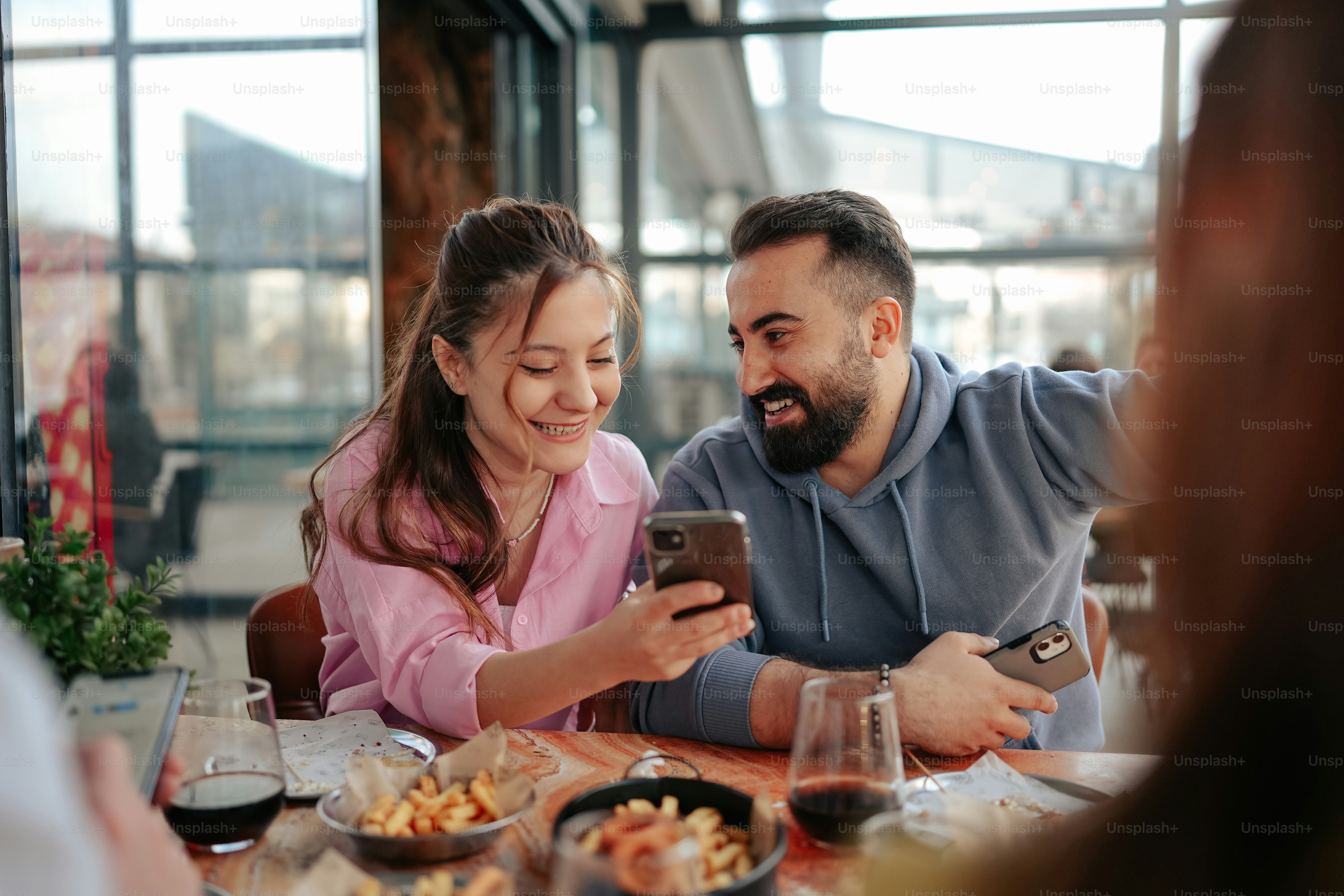 a man and woman sitting at a table looking at a cell phone