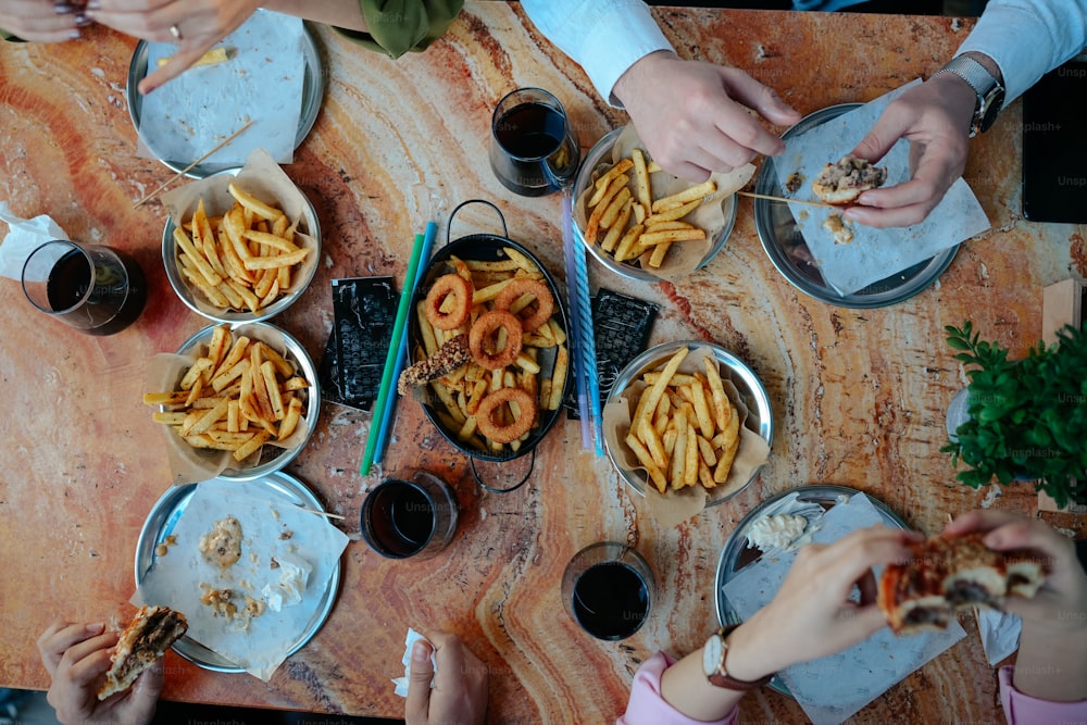 木製のテーブルの周りに座って食べ物を食べる人々のグループ
