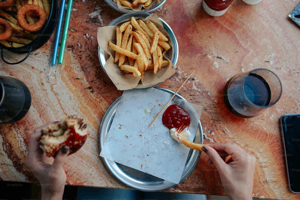 a person is eating french fries with ketchup and ketchup