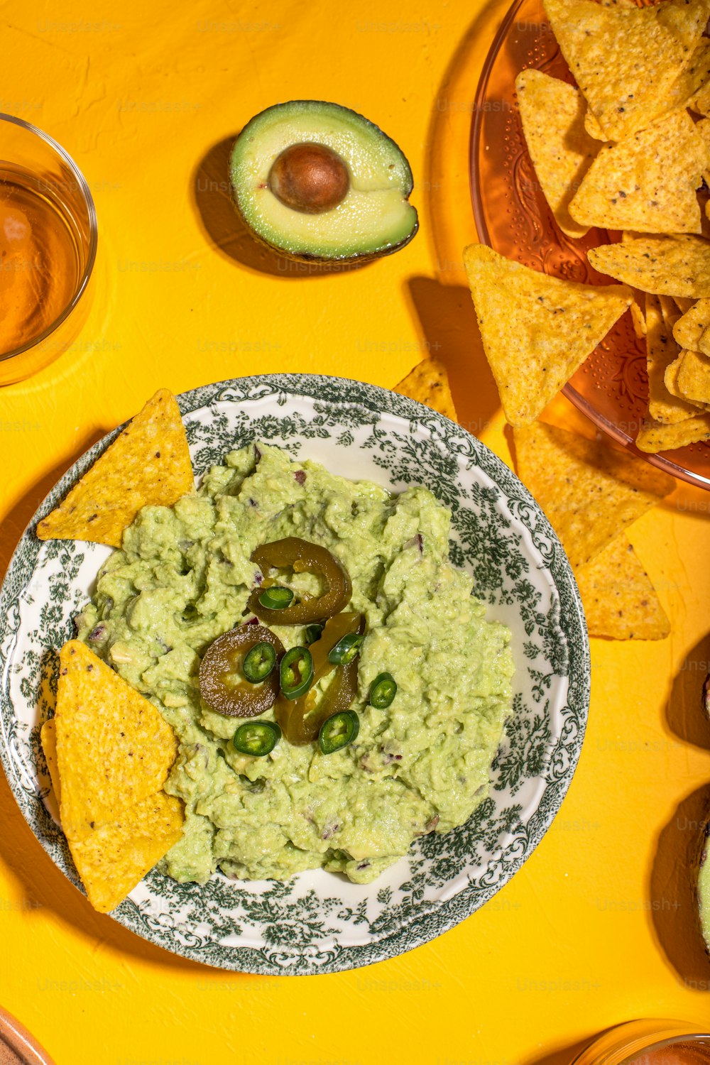a plate of guacamole and chips on a yellow table