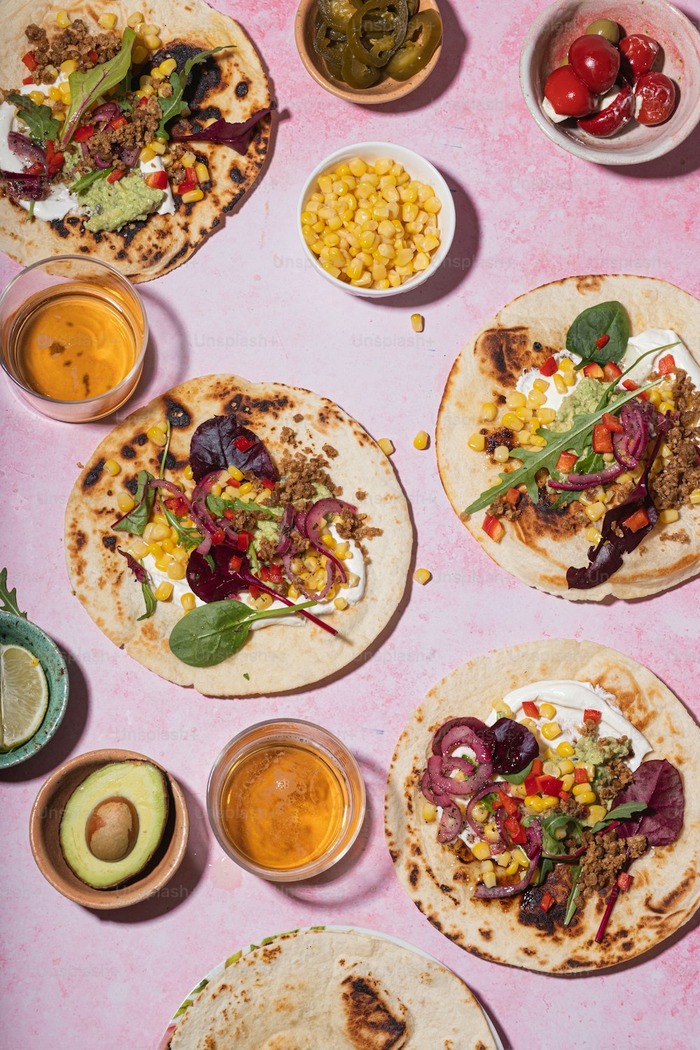 a table topped with lots of tacos covered in toppings