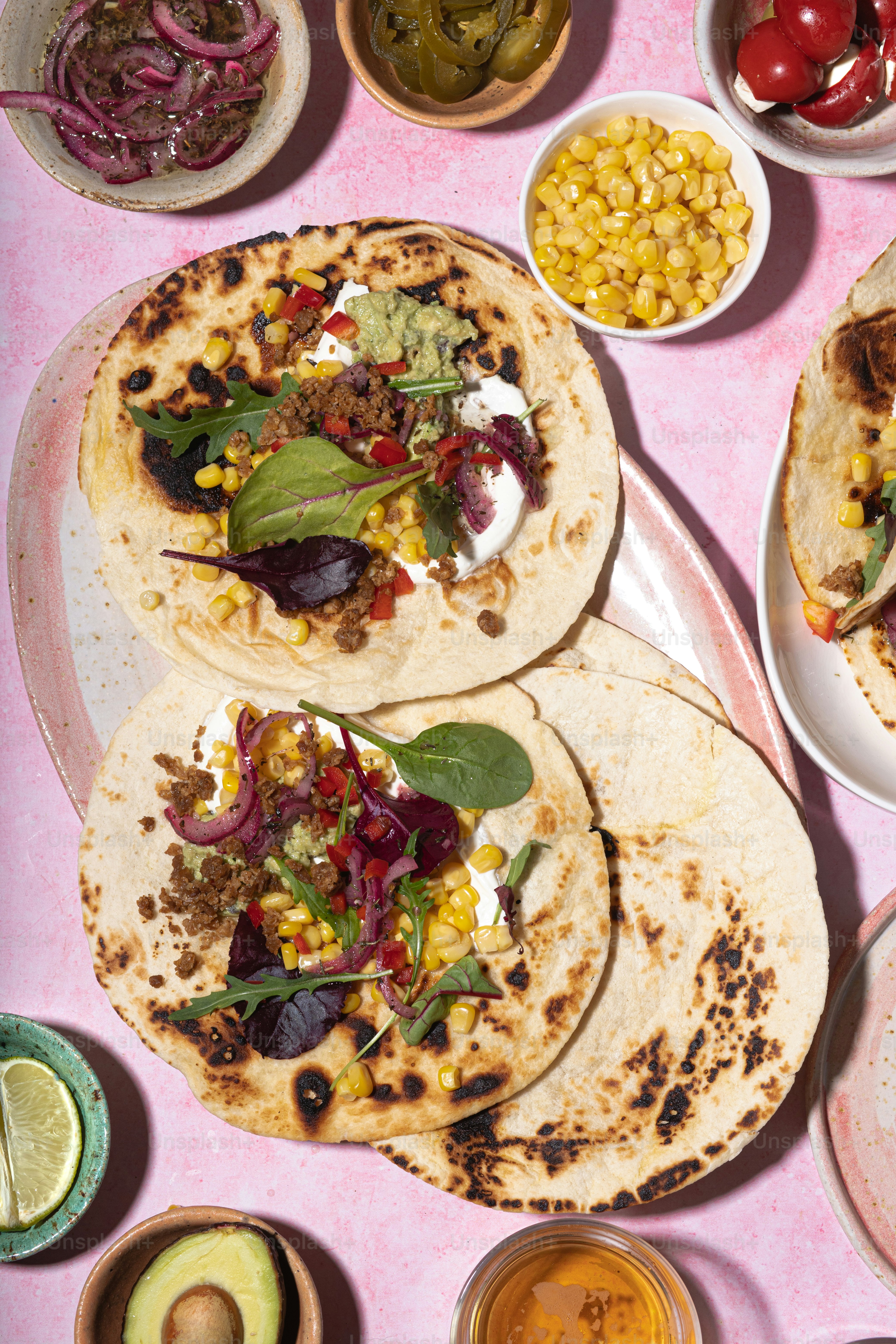 A table topped with lots of tacos covered in toppings photo – Food ...