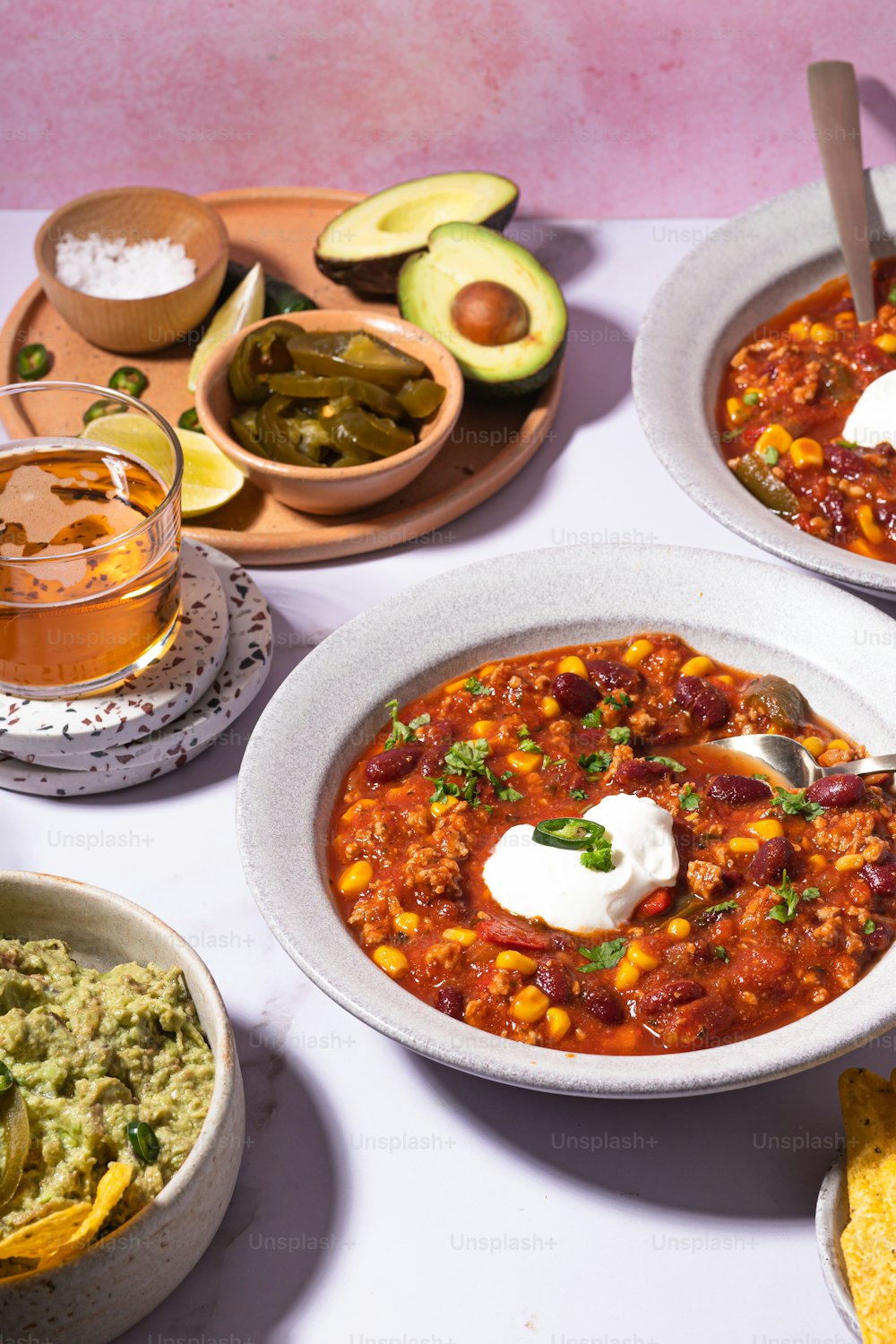a table topped with bowls of chili and guacamole