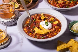 a bowl of chili with sour cream and tortilla chips