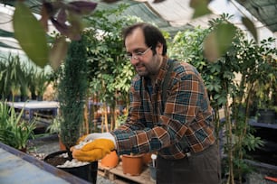a man in a greenhouse holding a potted plant