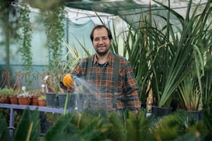 男が温室の植物に水をやっている