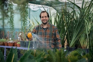 a man is watering plants in a greenhouse