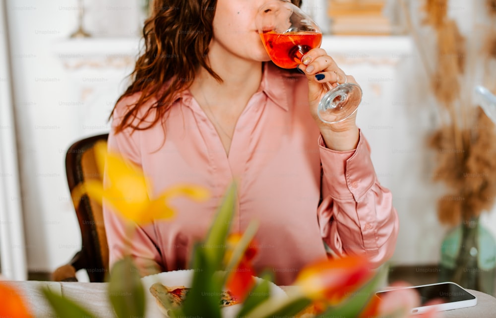 Eine Frau sitzt an einem Tisch und trinkt ein Glas Wein