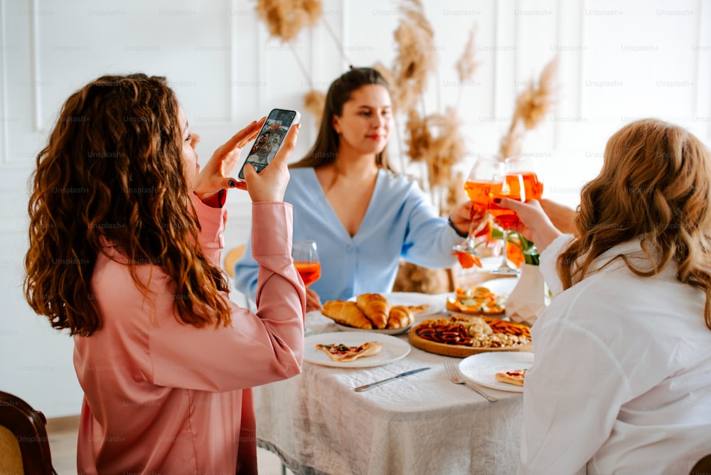 a group of women sitting around a table with food and drinks