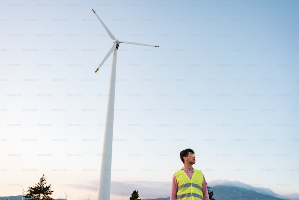 a man standing next to a wind turbine