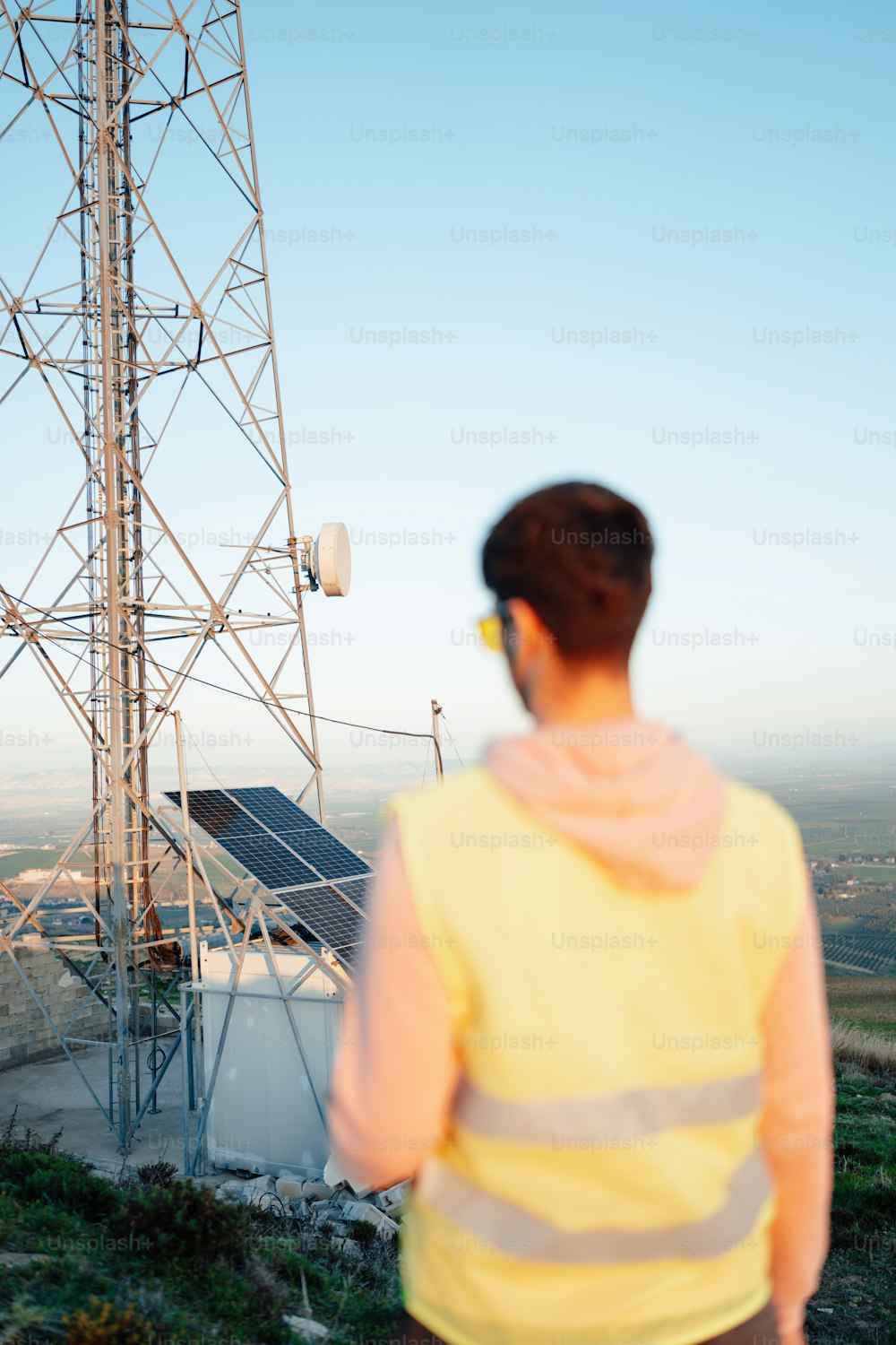 Un hombre parado frente a una torre de telefonía celular