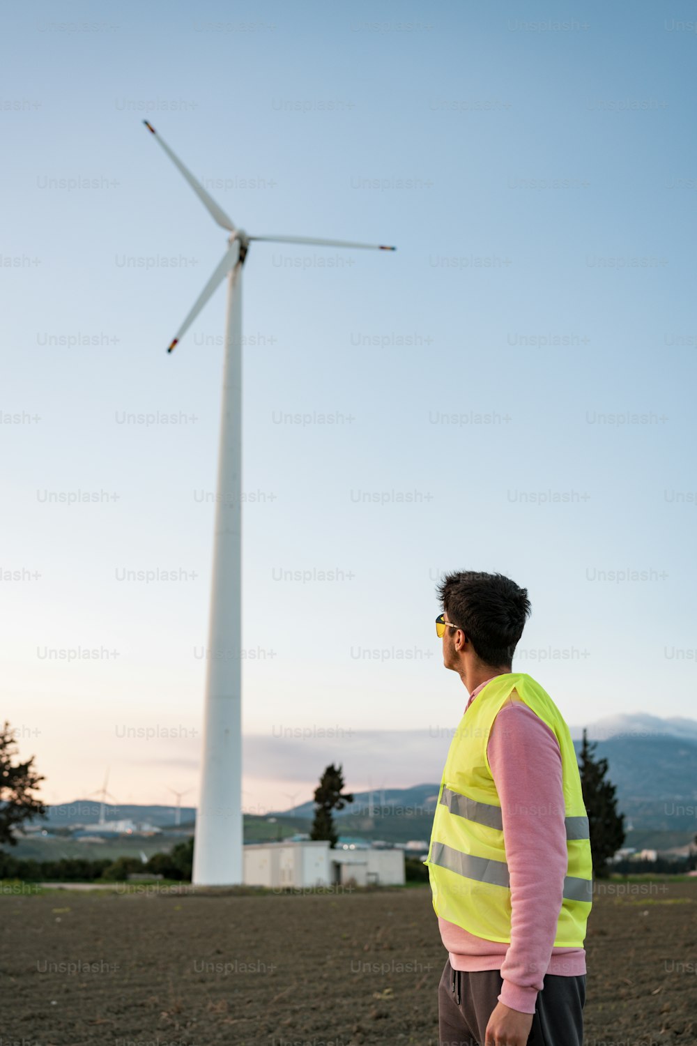 a man standing in front of a wind turbine