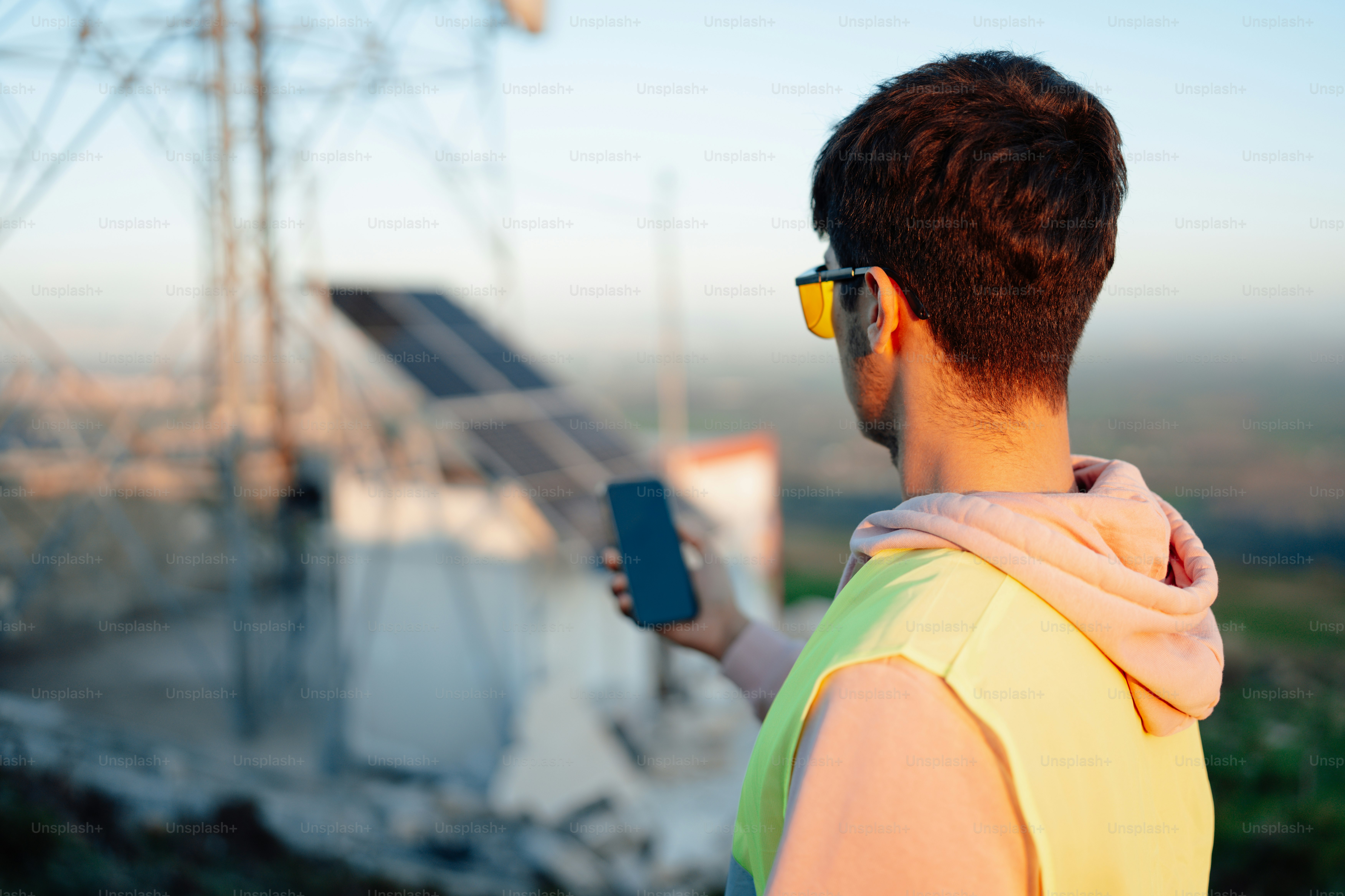 Un uomo in un gilet giallo che tiene un telefono cellulare
