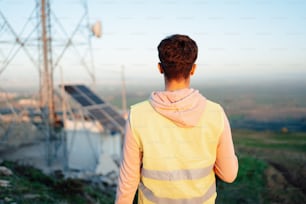 a man in a yellow jacket looking at a power line