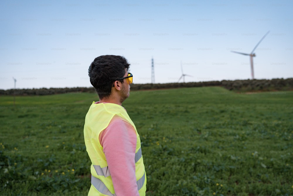 a man in a yellow vest standing in a field