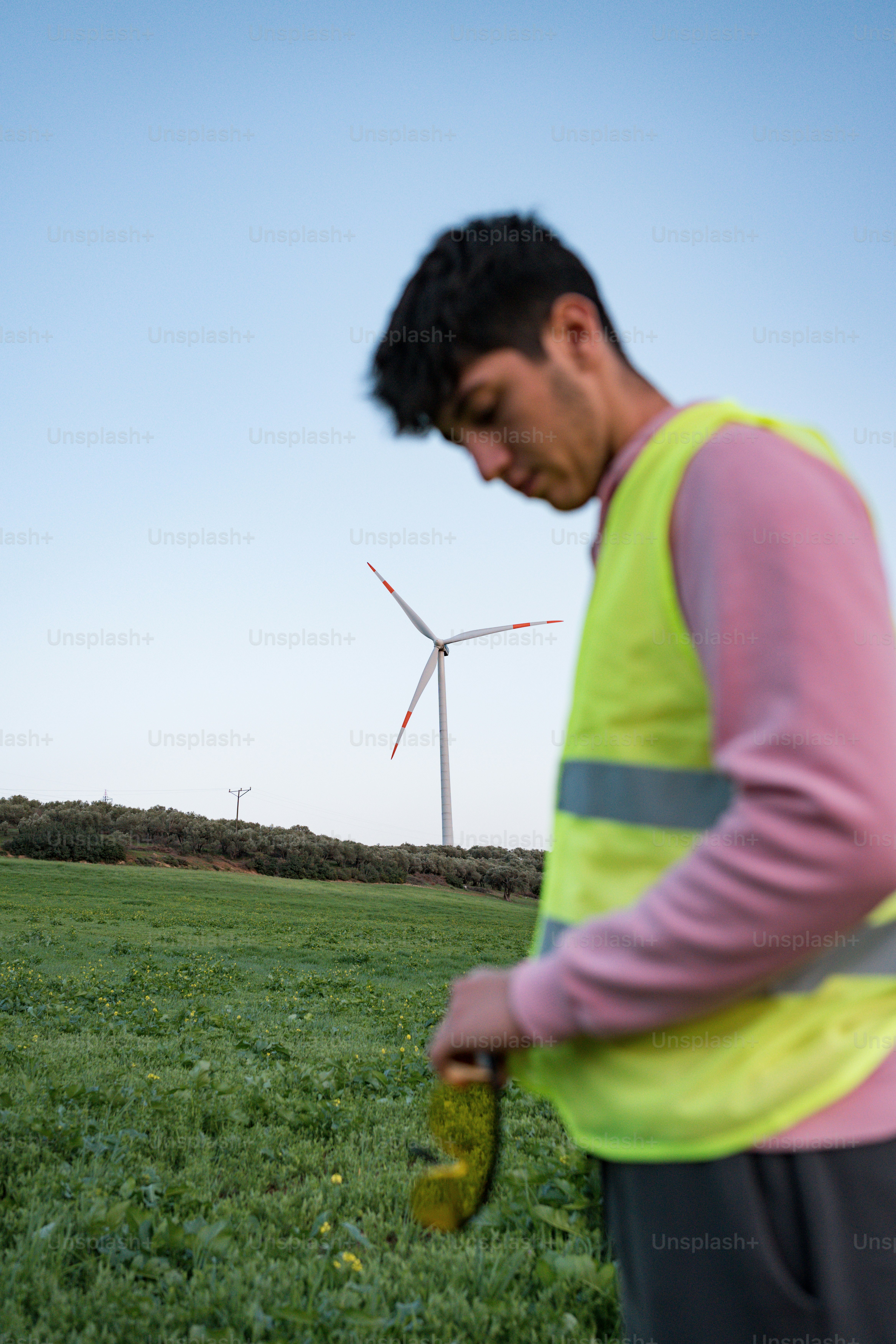 Un uomo in piedi in un campo con una turbina eolica sullo sfondo