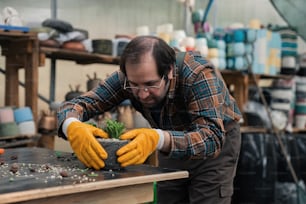 a man wearing yellow gloves and holding a plant