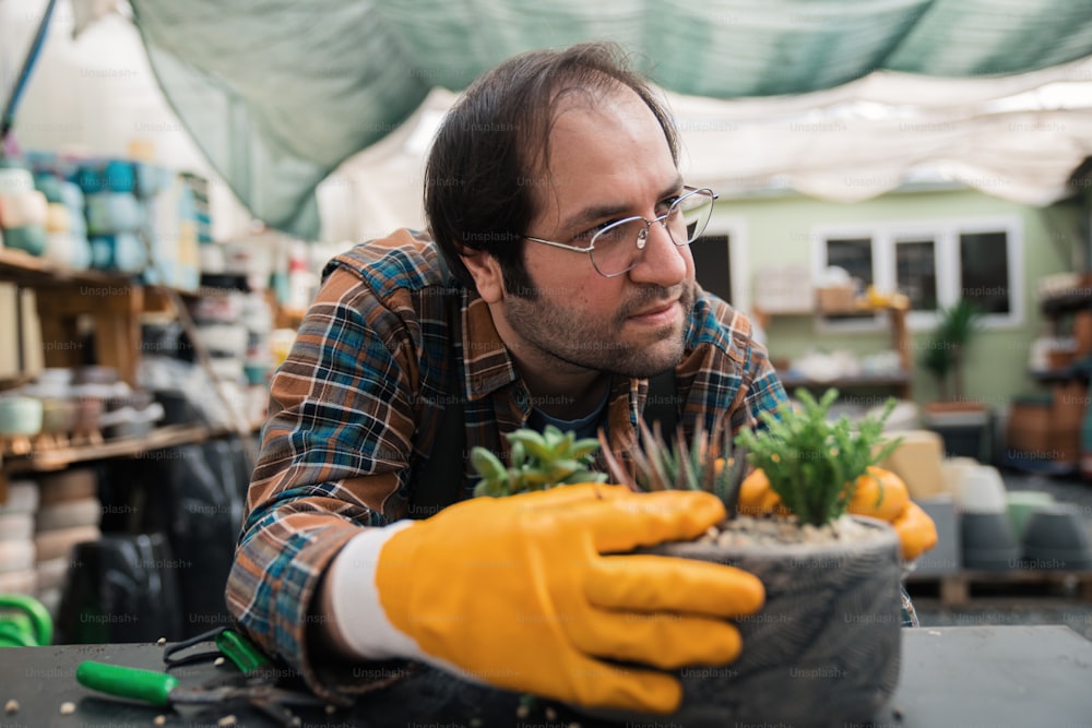 um homem vestindo luvas amarelas e segurando um vaso de planta