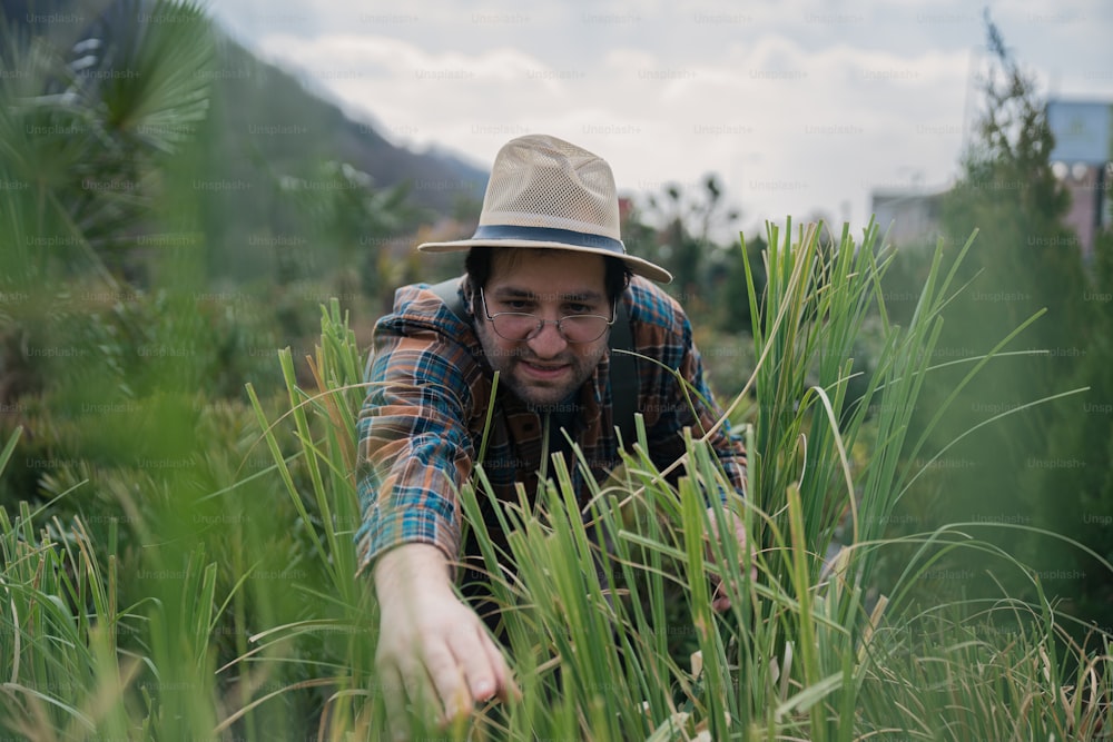 a man in plaid shirt and hat in tall grass