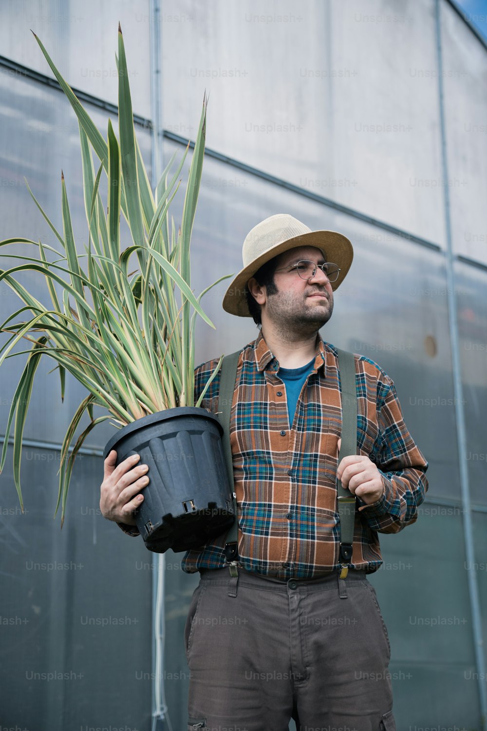 Ein Mann, der eine Topfpflanze vor einem Gebäude hält